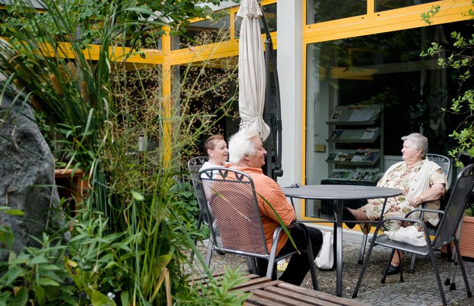 Drei Senioren sitzen draußen im Hinterhof