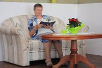 Eine Seniorin sitzt auf einem Sofa und liest