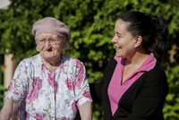 Eine ältere Dame wird von einer fröhlichen jüngeren Frau am Arm geführt.