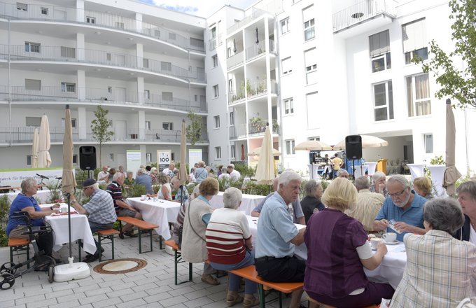 Viele Menschen sitzen im Innenhof des Wohn- und Pflegezentrums Flugfeld
