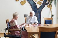 Zwei Seniorinnen sitzen am Tisch und spielen ein Brettspiel