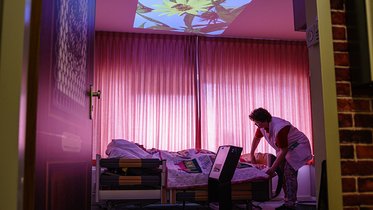 Abgedunkeltes Pflegezimmer mit Lichtprojektion an die Zimmerdecke