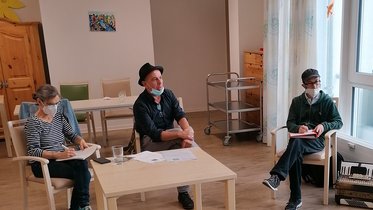 Drei Personen sitzen im Gemeinschaftsraum