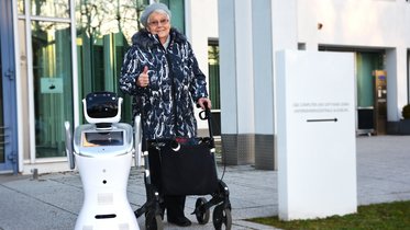 Roboter NIKA neben einer Seniorin mit Rollator